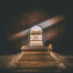 Beautiful tomb interior with a golden sarcophagus, illuminated by sunlight through an ornate archway.