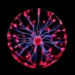 Close-up of a plasma globe with vibrant neon sparks against a dark background.
